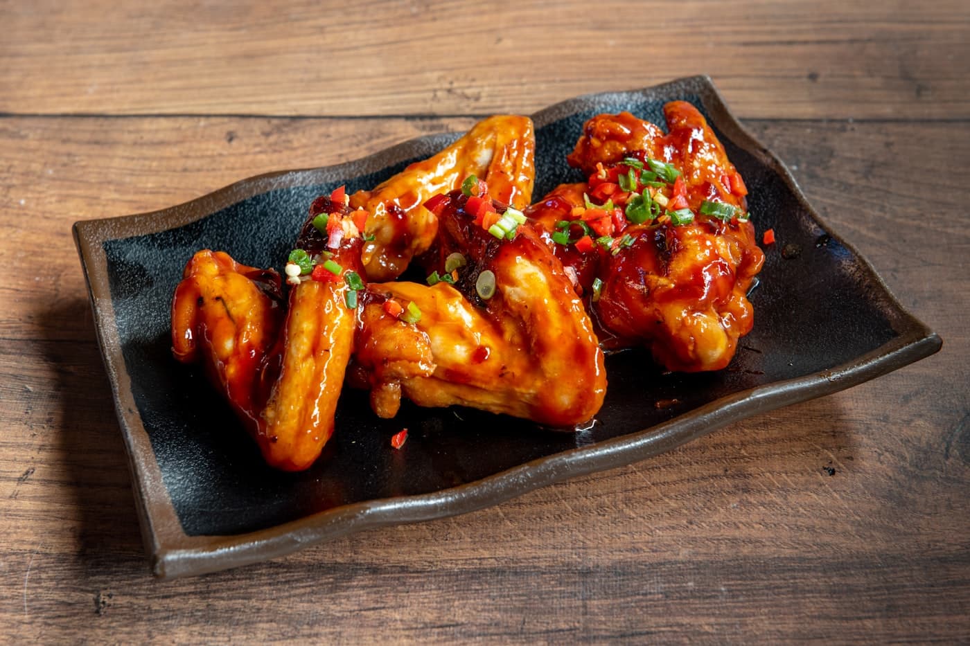 Glazed chicken wings on a black plate
